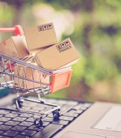 Online shopping and delivery service concept. Paper cartons in a shopping cart on a laptop keyboard, this image implies online shopping that customer order things from retailer sites via the internet.